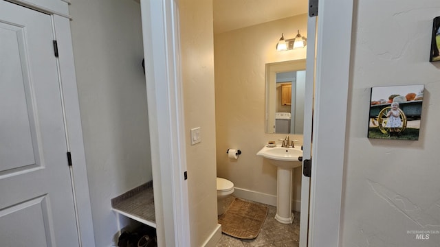 bathroom featuring toilet, tile patterned flooring, washer / clothes dryer, and sink