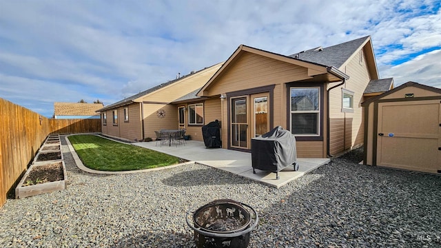 rear view of house with an outdoor fire pit, a patio, and a shed