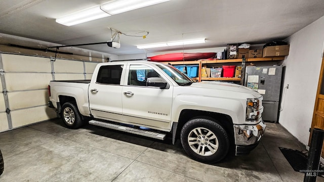 garage with a garage door opener and stainless steel refrigerator