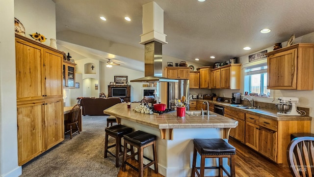 kitchen featuring tile countertops, ceiling fan, a kitchen island with sink, vaulted ceiling, and a breakfast bar