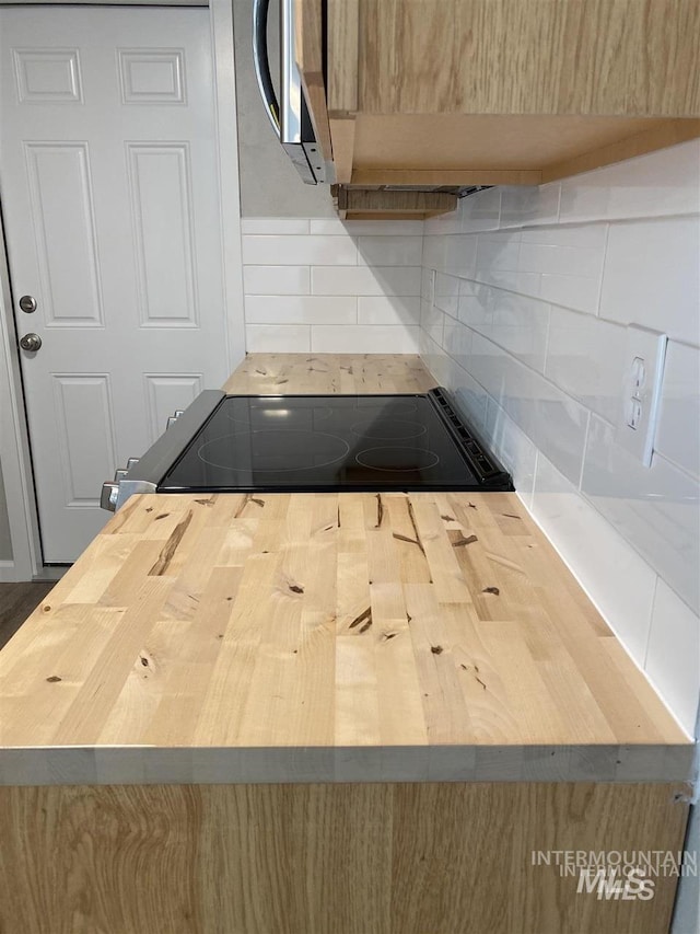 kitchen with butcher block counters, backsplash, and range with electric cooktop