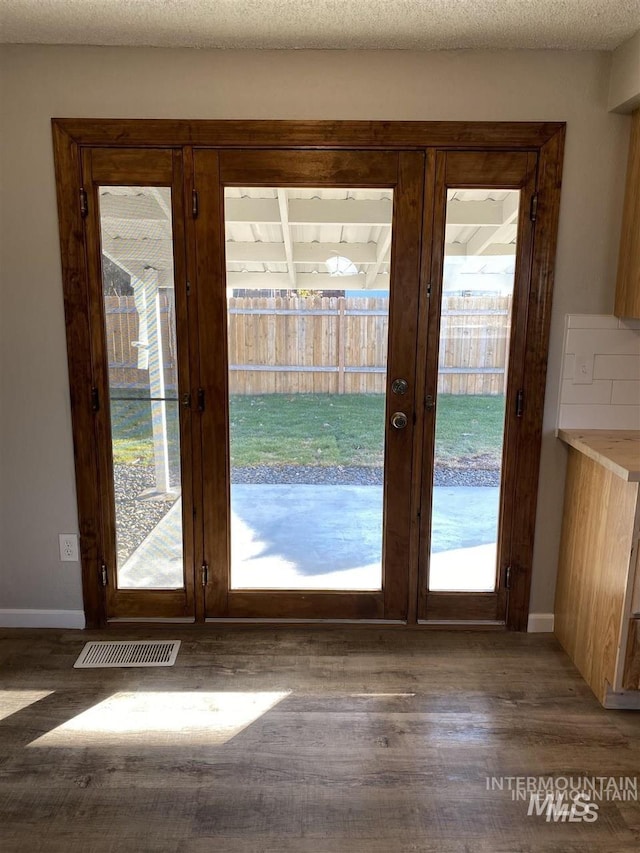 doorway featuring a textured ceiling, visible vents, wood finished floors, french doors, and baseboards