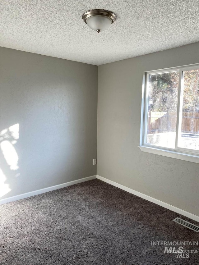 carpeted spare room with visible vents, baseboards, and a textured ceiling