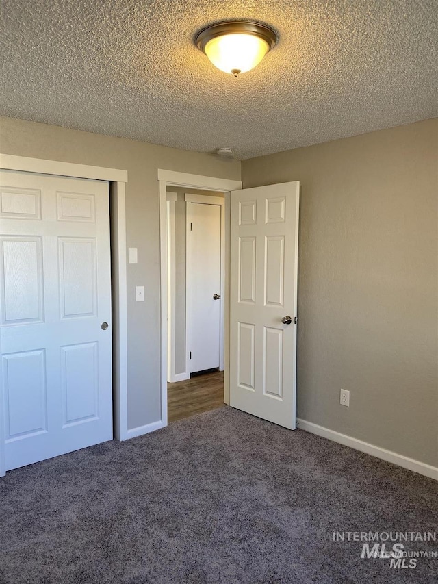 unfurnished bedroom featuring a closet, baseboards, carpet flooring, and a textured ceiling