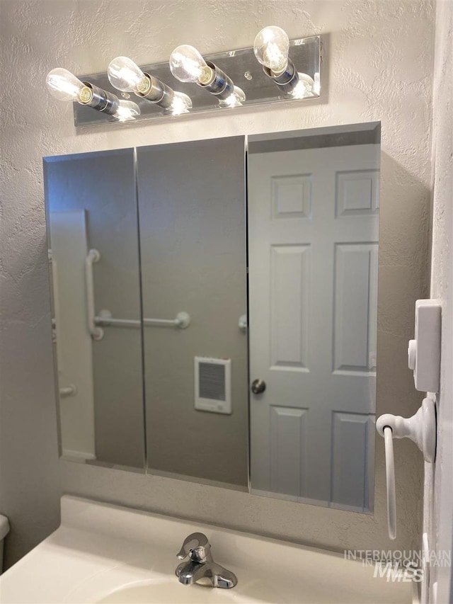 bathroom featuring visible vents, vanity, and a textured wall