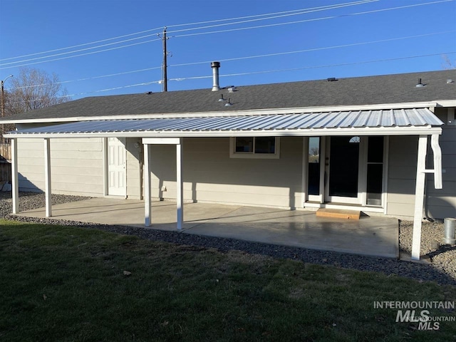 rear view of property with a patio, a yard, and metal roof
