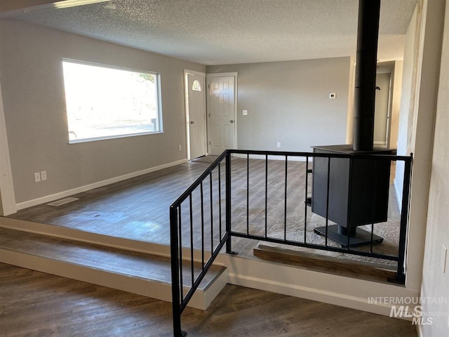 staircase with a textured ceiling, wood finished floors, baseboards, and visible vents
