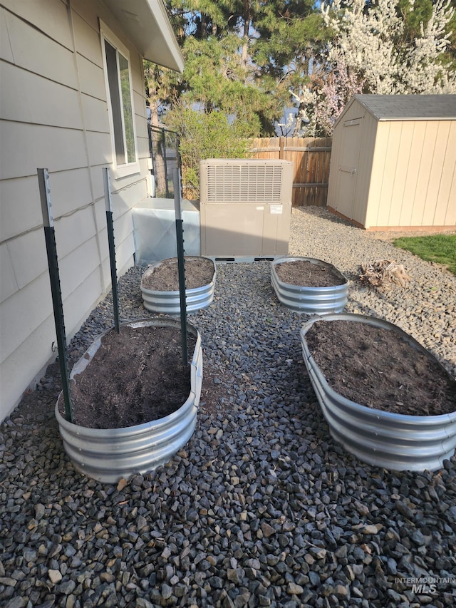 view of yard with a storage shed, a vegetable garden, fence, cooling unit, and an outbuilding