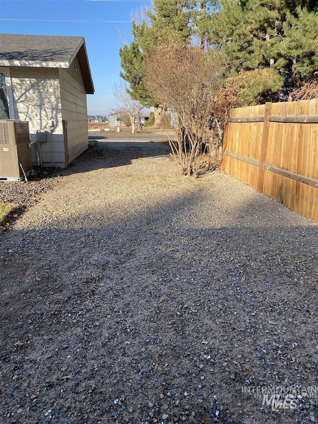 view of yard with central AC unit and fence
