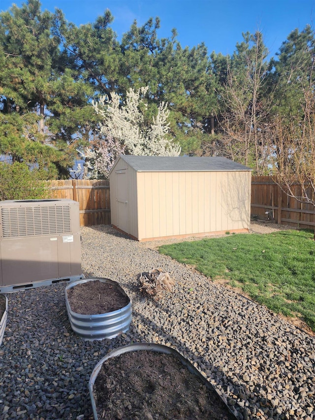 view of yard featuring central AC unit, a fenced backyard, an outdoor structure, and a storage unit