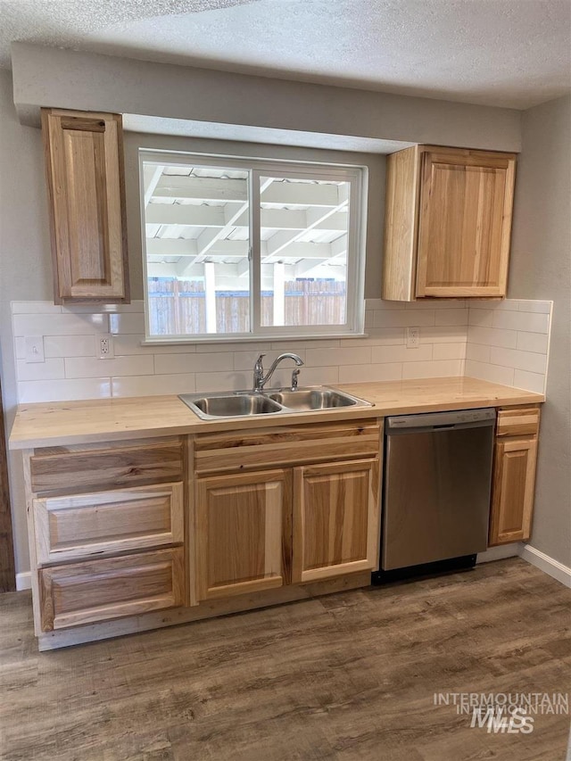 kitchen featuring dark wood finished floors, a textured ceiling, dishwasher, a sink, and backsplash