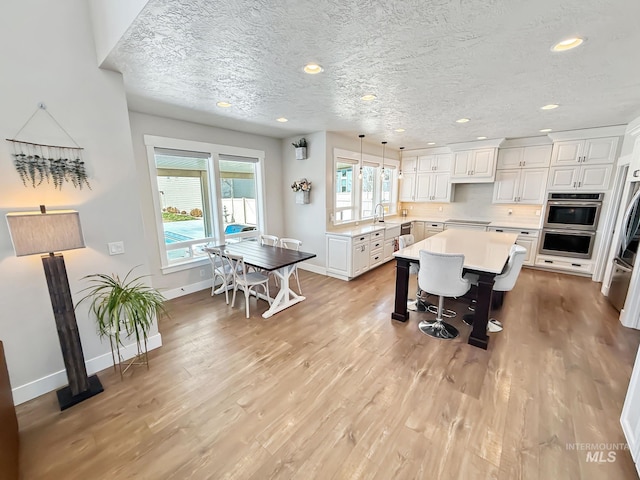 7063 S Pear Blossom, Meridian, ID 83642 - kitchen with baseboards, a kitchen breakfast bar, light countertops, white cabinetry, and light wood-style floors