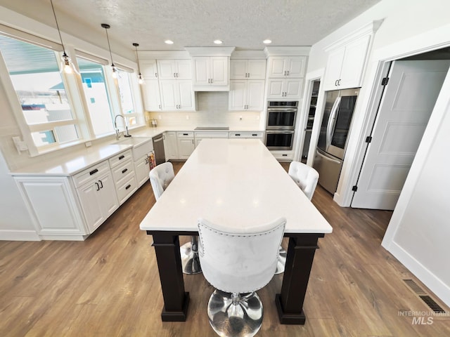 7063 S Pear Blossom, Meridian, ID 83642 - kitchen with visible vents, a center island, appliances with stainless steel finishes, a sink, and backsplash