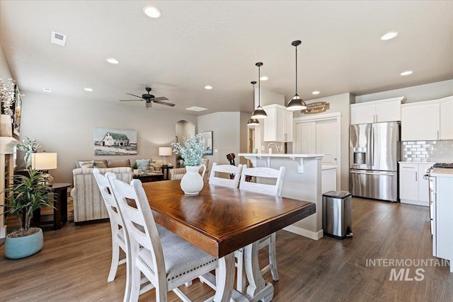 dining room with dark wood-style flooring, arched walkways, a ceiling fan, recessed lighting, and visible vents