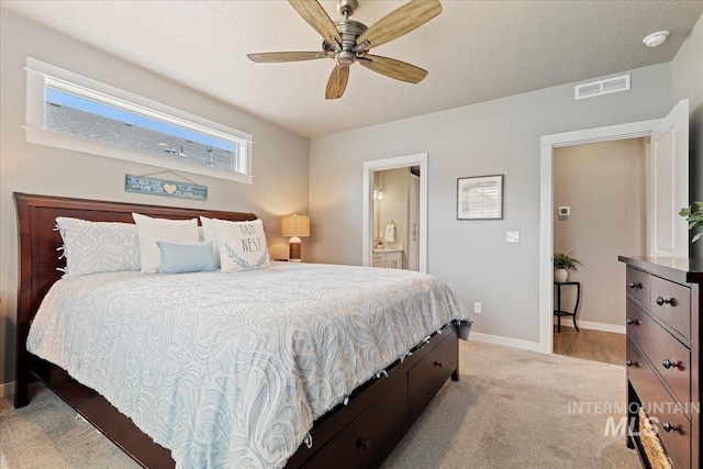 bedroom featuring ceiling fan, light carpet, ensuite bath, baseboards, and visible vents