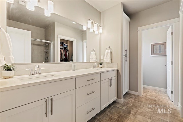 full bath with double vanity, a walk in closet, a shower stall, and a sink