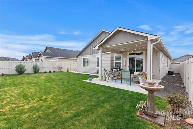 rear view of house featuring a lawn, a fenced backyard, board and batten siding, and a patio area