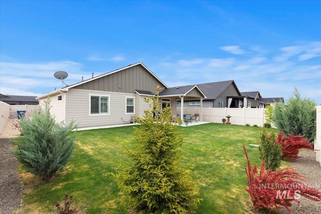 back of property with board and batten siding, a yard, fence, and a patio area
