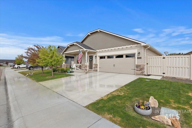 craftsman inspired home featuring a garage, a front yard, driveway, and stone siding