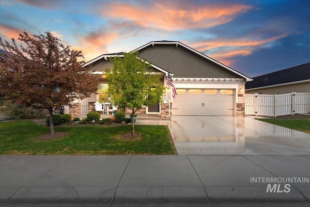 view of front of house featuring fence, an attached garage, stone siding, concrete driveway, and a lawn