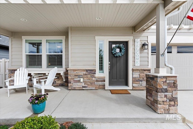 entrance to property featuring a porch and stone siding
