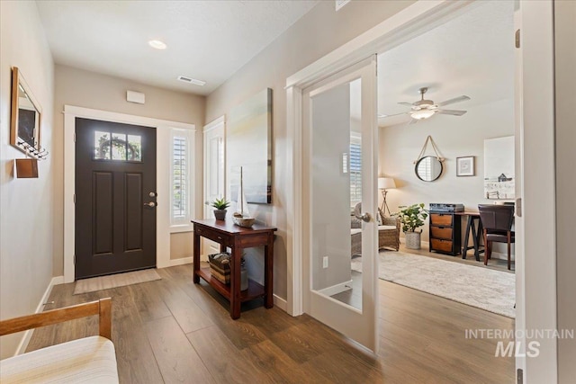 entryway featuring a ceiling fan, baseboards, visible vents, and wood finished floors