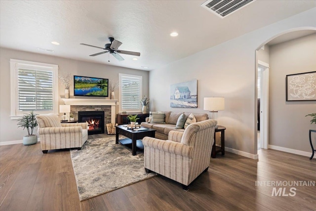 living area with dark wood-style flooring, arched walkways, a ceiling fan, and baseboards