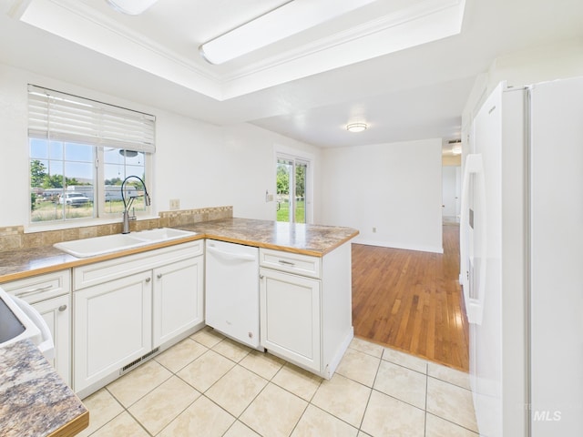 1673 Thomas, Emmett, ID 83617 - kitchen featuring white appliances, a tray ceiling, a peninsula, light tile patterned floors, and white cabinetry
