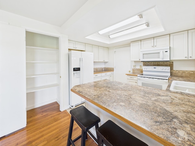 1673 Thomas, Emmett, ID 83617 - kitchen featuring white appliances, a raised ceiling, a peninsula, light wood finished floors, and white cabinets