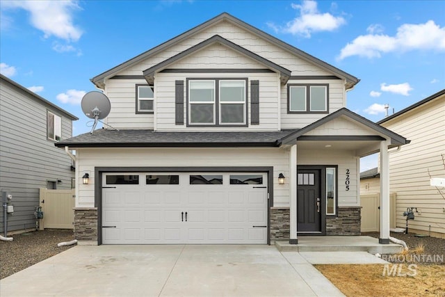 craftsman-style home featuring an attached garage, stone siding, concrete driveway, and fence