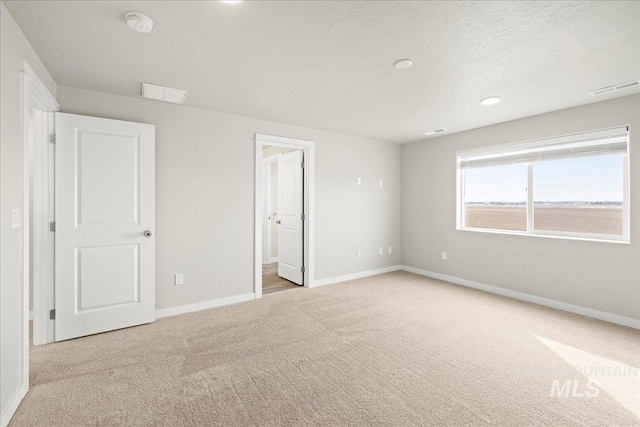 unfurnished bedroom featuring a textured ceiling, carpet floors, visible vents, and baseboards