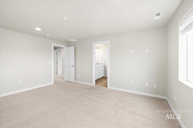 unfurnished bedroom with baseboards, connected bathroom, visible vents, and light colored carpet