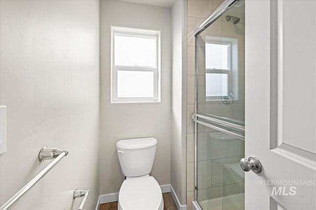 full bath with toilet, plenty of natural light, a shower stall, and baseboards