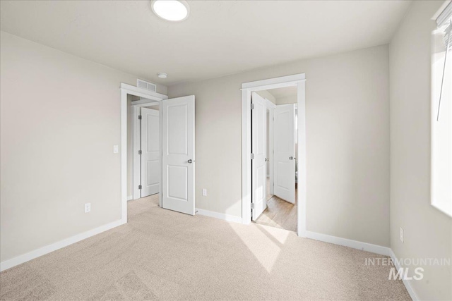 unfurnished bedroom with light colored carpet, visible vents, and baseboards