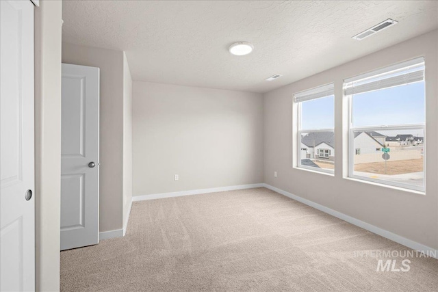 unfurnished room featuring carpet, visible vents, a textured ceiling, and baseboards