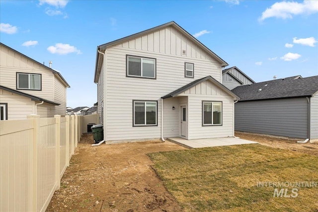 back of house featuring a patio, fence, board and batten siding, and a yard