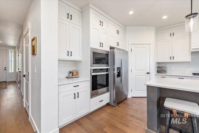 11328 W Campanula Dr, Star, ID 83669 - kitchen featuring stainless steel appliances, wood finished floors, light countertops, tasteful backsplash, and white cabinets