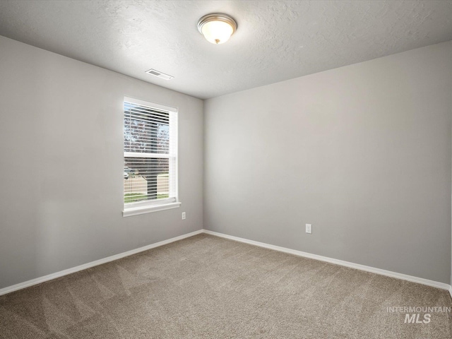 empty room featuring carpet floors, baseboards, and a textured ceiling