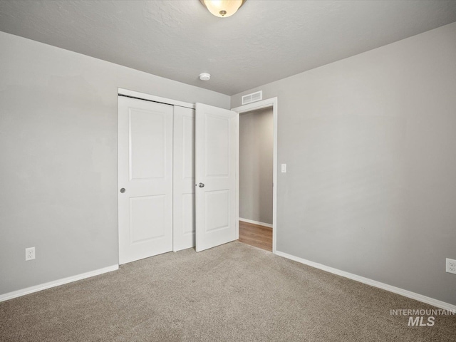 unfurnished bedroom featuring carpet, a closet, baseboards, and a textured ceiling