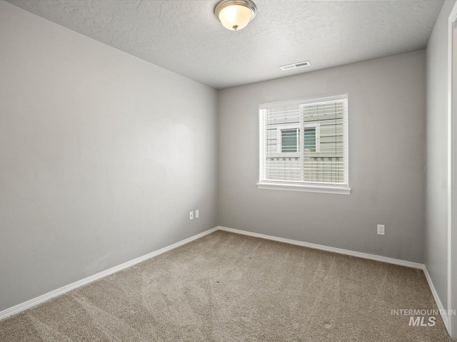 carpeted empty room with a textured ceiling and baseboards