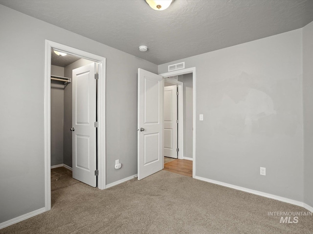 unfurnished bedroom with carpet flooring, a spacious closet, baseboards, and a closet
