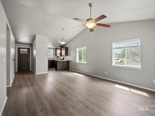 unfurnished living room with baseboards, dark wood finished floors, a ceiling fan, and high vaulted ceiling