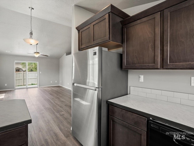 kitchen featuring freestanding refrigerator, a textured ceiling, dark brown cabinetry, baseboards, and black dishwasher