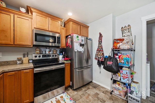909 Arrow Wood Ct, Twin Falls, ID 83301 - kitchen with stainless steel appliances, baseboards, recessed lighting, light countertops, and stone finish flooring
