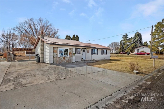 ranch-style house with metal roof, a front lawn, and a chimney