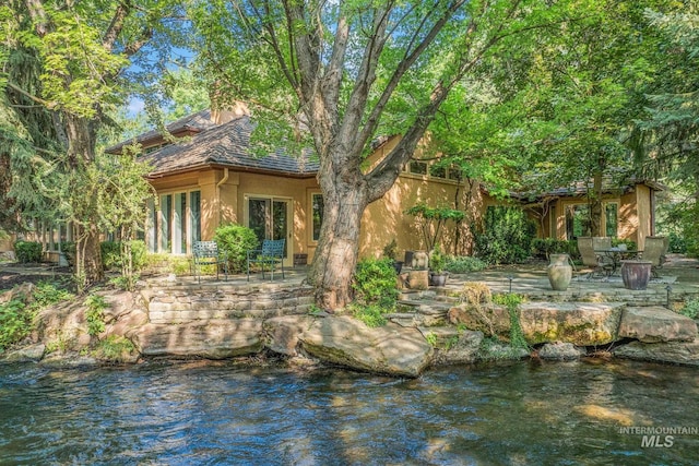 rear view of property with a patio and a water view