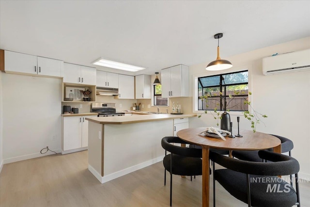 1223 N Mckinney St, Boise, ID 83704 - kitchen featuring an AC wall unit, under cabinet range hood, white cabinets, light wood finished floors, and stainless steel electric range oven