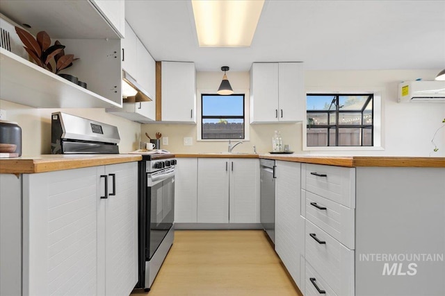 1223 N Mckinney St, Boise, ID 83704 - kitchen featuring appliances with stainless steel finishes, a wall mounted air conditioner, white cabinetry, under cabinet range hood, and light wood-style flooring