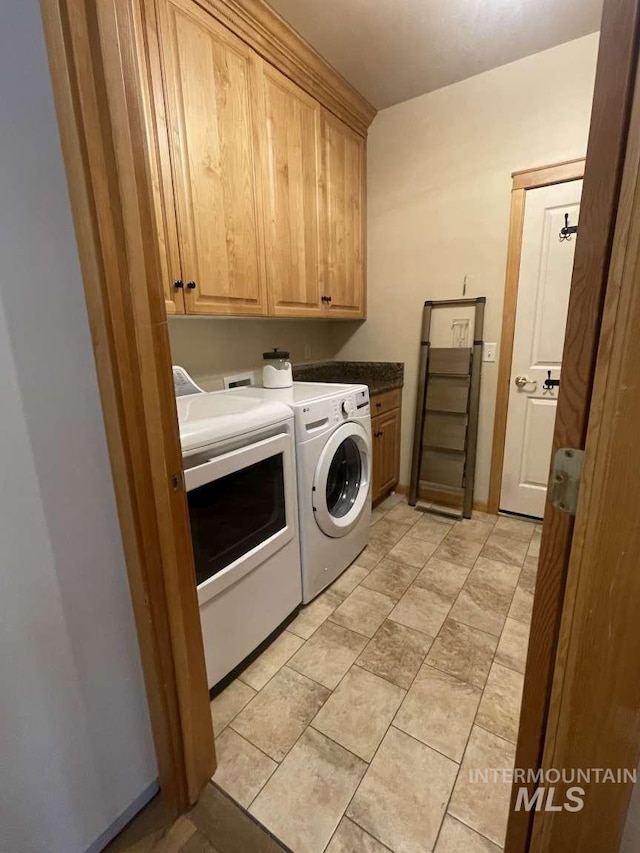 clothes washing area featuring independent washer and dryer and cabinets