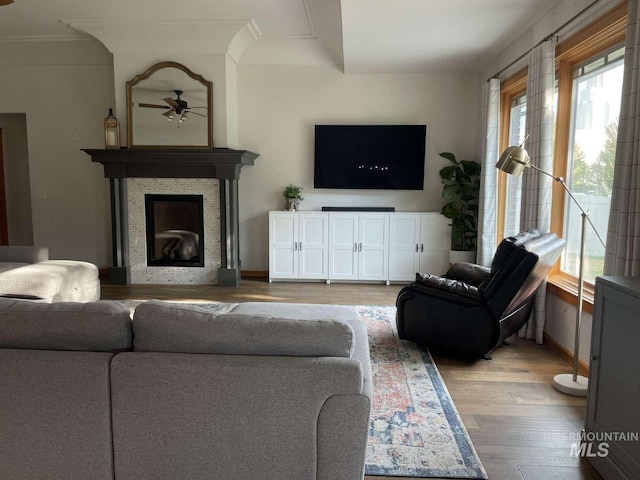 living room featuring hardwood / wood-style flooring, crown molding, and a fireplace